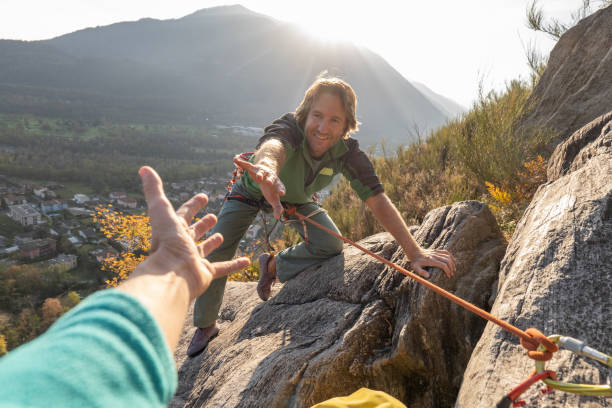 pov bras baissé au jeune homme grimpant sur une paroi rocheuse - rock climbing mountain climbing women achievement photos et images de collection