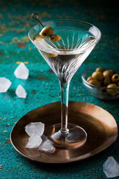 緑の色のテーブルにオリーブを飾ったマティーニグラスの汚れたマティーニカクテル - martini martini glass dirty martini olive ストックフォトと画像