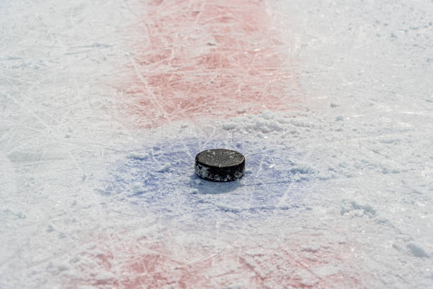 czarny stary krążek leży pośrodku koła wrzutowego na wyciętym na łyżwach lodowisku hokejowym. - ice hockey ice skate equipment black zdjęcia i obrazy z banku zdjęć