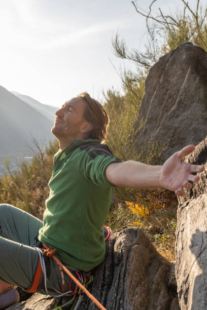 male mountain climber arms outstretched on mountain top - conquering adversity wilderness area aspirations achievement imagens e fotografias de stock