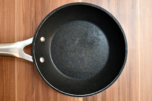 Damaged bottom of a frying pan. Empty pan on a wooden table.