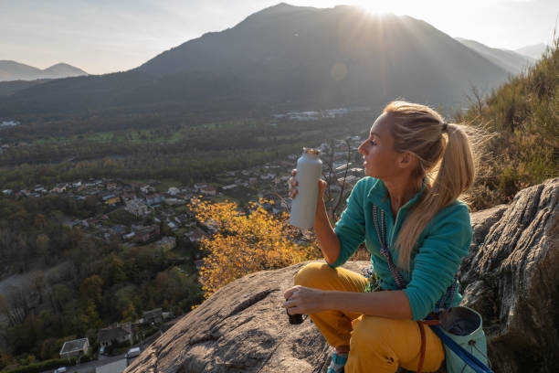 female mountain climber takes a break to enjoy the view - conquering adversity wilderness area aspirations achievement imagens e fotografias de stock