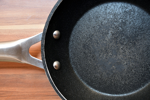 Damaged bottom of a frying pan. Empty pan on a wooden table.