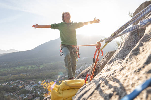 istock Male mountain climber arms outstretched on mountain top 1354857589