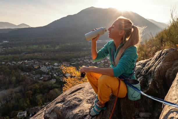 female mountain climber takes a break to enjoy the view - conquering adversity wilderness area aspirations achievement imagens e fotografias de stock