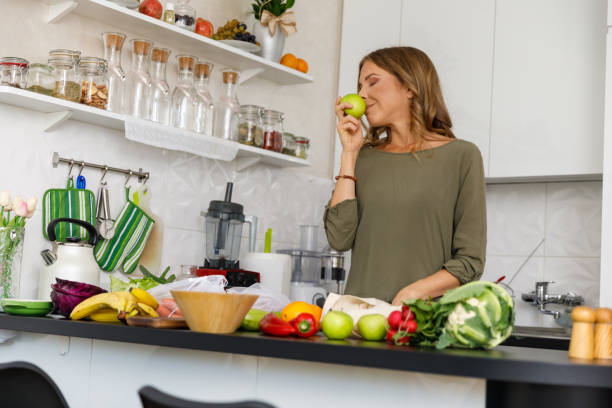 istock Happy woman smelling a green apple while unpacking groceries 1354857914