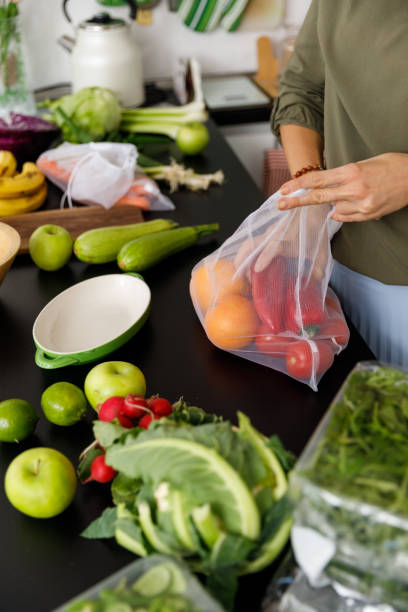 istock Unrecognizable woman unpacking fruit and veg on a kitchen counter 1354858176