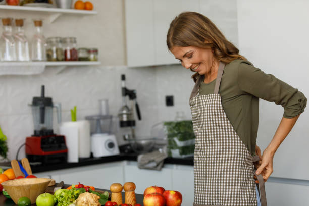 istock Smiling woman putting on an apron before preparing food 1354858761