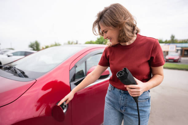 Woman holds a charging plug for an electric car stock photo
