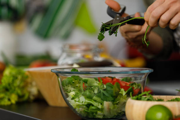 istock Woman using kitchen scissors and cutting up fresh parsley into a salad she is preparing 1354859085