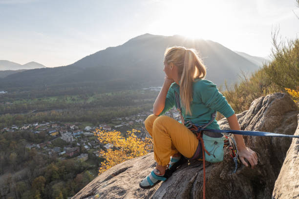 female mountain climber takes a break to enjoy the view - conquering adversity wilderness area aspirations achievement imagens e fotografias de stock