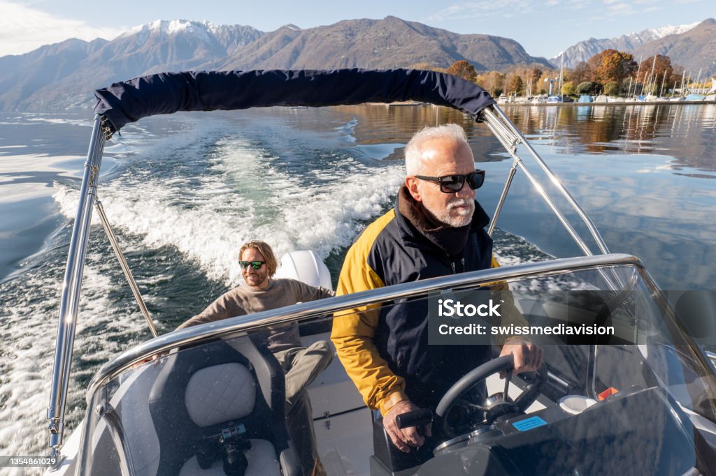 Father and son on pilot boat enjoy lake in Autumn Male boat captain and his son enjoying the lake and the mountains in Autumn.
Early retirement concept Senior Adult Stock Photo