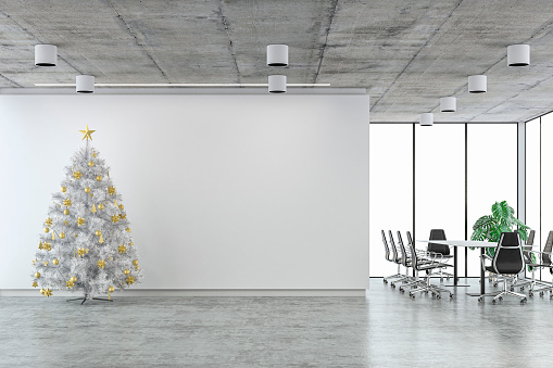Empty office interior on concrete floor with a white and golden Christmas tree in front of an empty white wall background and copy space, conference table and windows in background. 3D rendered image.