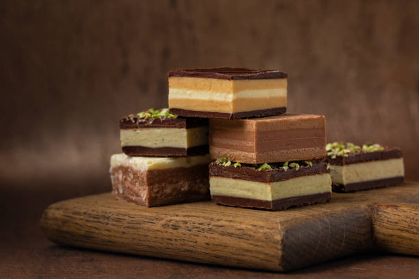 istock Italian cremino - chocolate typical shape is a cube,  originally from Piedmont, composed by different layers,  made with gianduja chocolate, coffee, pistacchio or hazelnut paste. On brown background. 1354862319