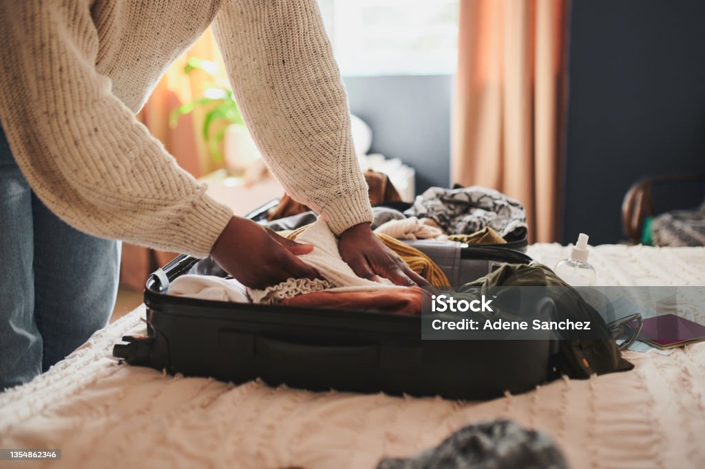 Cropped shot of an unrecognizable woman packing her things into a suitcase at home before travelling I can't leave this behind Suitcase Stock Photo
