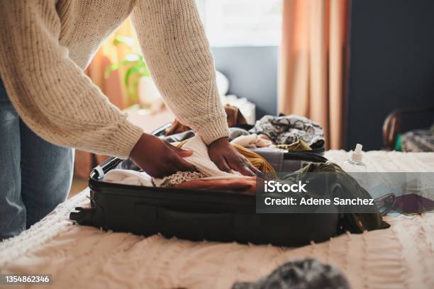 Cropped Shot Of An Unrecognizable Woman Packing Her Things Into A Suitcase At Home Before Travelling Stock Photo - Download Image Now