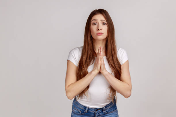 istock Woman holding hands in prayer and asking for help with pleading imploring expression, full of hope. 1354862577