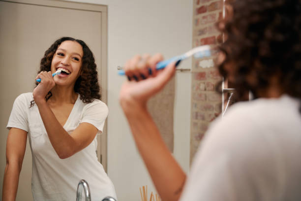 joven mujer multicultural saludable cantando en el cepillo de dientes como un micrófono en el baño. feliz, bailando en el baño moderno - ewan fotografías e imágenes de stock