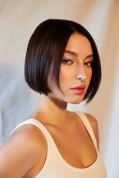 Photo of Portrait beauty woman short hair fashion coloring. Dark hair coloring, short haircut chocolate color. Beautiful clean facial skin, natural makeup, strong hair