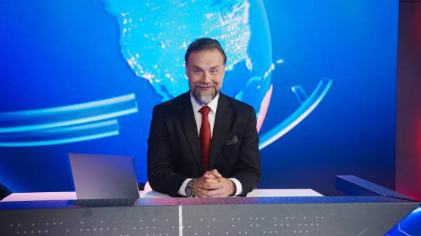 istock Live News Studio with Handsome Male Newscaster Reporting on a Story Smiling on Camera. Television Newsroom Channel with Professional Presenter, Anchor Talking 1354865963