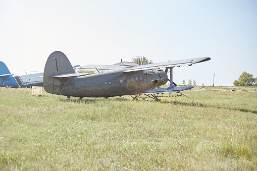 An old Soviet AN 2 aircraft stands at the airfield in the green.