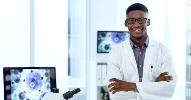 Shot of a young male doctor standing with his arms crossed in an office at work This is where the magic happens african american scientist stock pictures, royalty-free photos & images