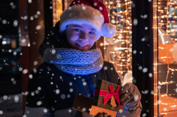 istock Boy in Santas hat with gifts box looking and dreaming 1354871652