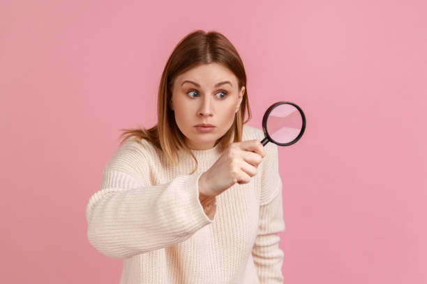 istock Woman looking through magnifying glass, spying, finding out something, exploring crime scene. 1354872434