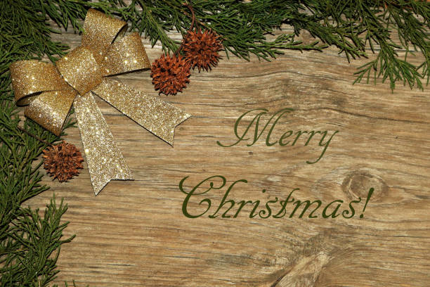 istock Gold Glitter Bow and Cedar Branches on Wood with Merry Christmas Text 1354874110