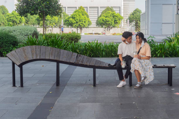 couple assis sur un banc tordu, marina bay - love clothing human relationship heterosexual couple photos et images de collection