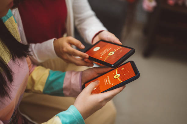азиатская семья, показывающая цифровой конверт hongbao или e-red, отправляет на смартфон - hongbao стоковые фото и изображения