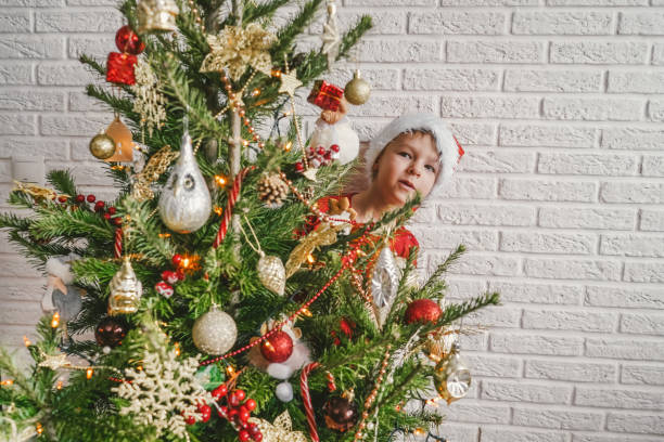 little child with decorated christmas tree, copy space. - christmas child little boys peeking imagens e fotografias de stock