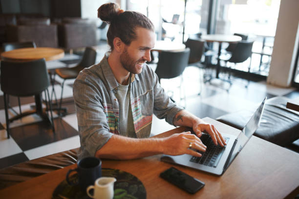 istock Shot of a young businessman teleworking from a cafe while using his laptop 1354875951