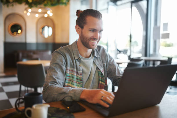 istock Shot of a young businessman teleworking from a cafe while using his laptop 1354875954