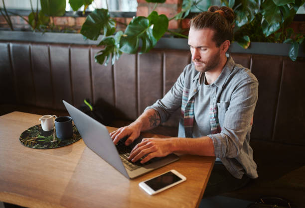 istock Shot of a young businessman teleworking from a cafe while using his laptop 1354876021