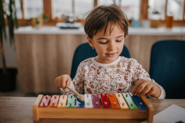 One girl, little girl is playing with xylophone at home.
