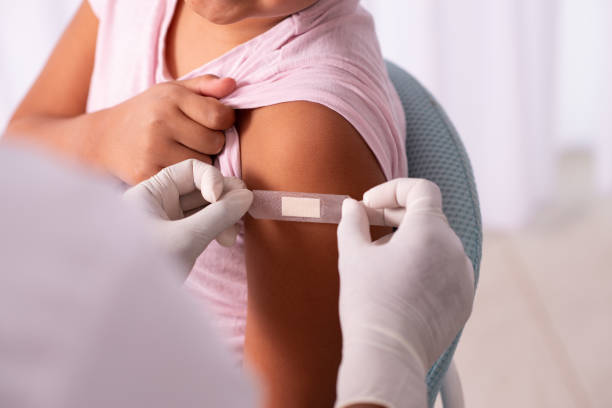 Doctor putting plaster at child's hand after injection of a vaccine. Medical healthcare worker putting a bandage on the child's arm after vaccination. herd immunity photos stock pictures, royalty-free photos & images