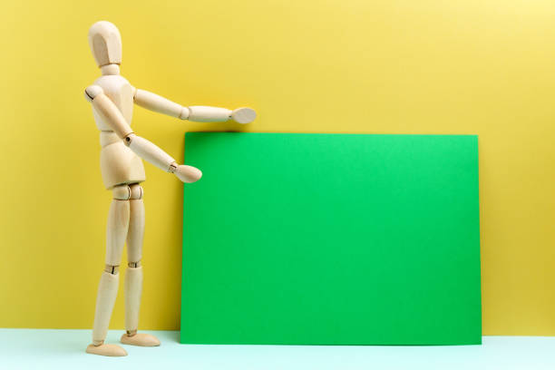 istock Wooden man presents empty space for your text copy. Green background 1354877930