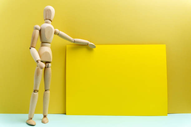 istock Wooden Human mannequin talking or presentation, standing talking, empty space for Text. Yellow background 1354878178
