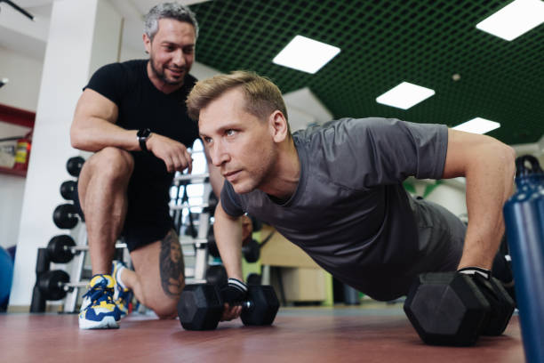 istock Young man has workout with personal trainer in the gym 1354878397