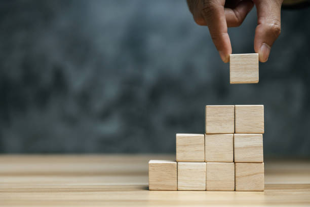 businessman hand putting blank wooden cube block stack on dark background with copy space for input text, icon, trend, creative idea, finance, leadership, strategy, business, online marketing concept