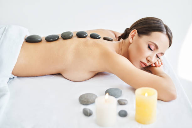istock Young female relaxing in spa salon with hot stones on her back 1354882728