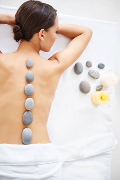 schöne junge frau, die sich während der hot-stone-massage entspannt - massaging spa treatment stone massage therapist stock-fotos und bilder