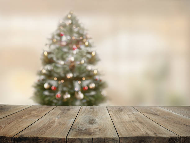istock Empty wooden table background with blurred christmas fir tree. 1354883099