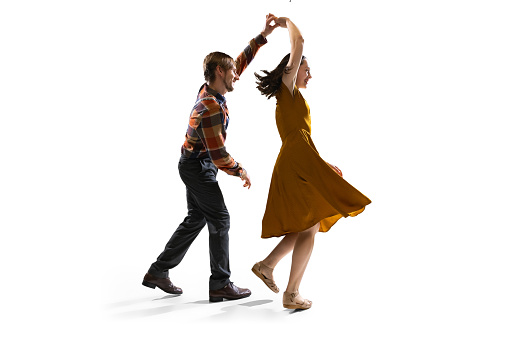 Social dansing.Two dancers, young man and girl in old-school fashioned attire dancing rock-and-roll isolated on white background. Artists in motion and action. Concept of culture, art, music, style, ad