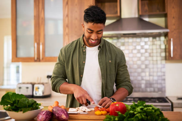 foto de un joven preparando verduras para cocinar una comida - dieta paleolítica fotografías e imágenes de stock