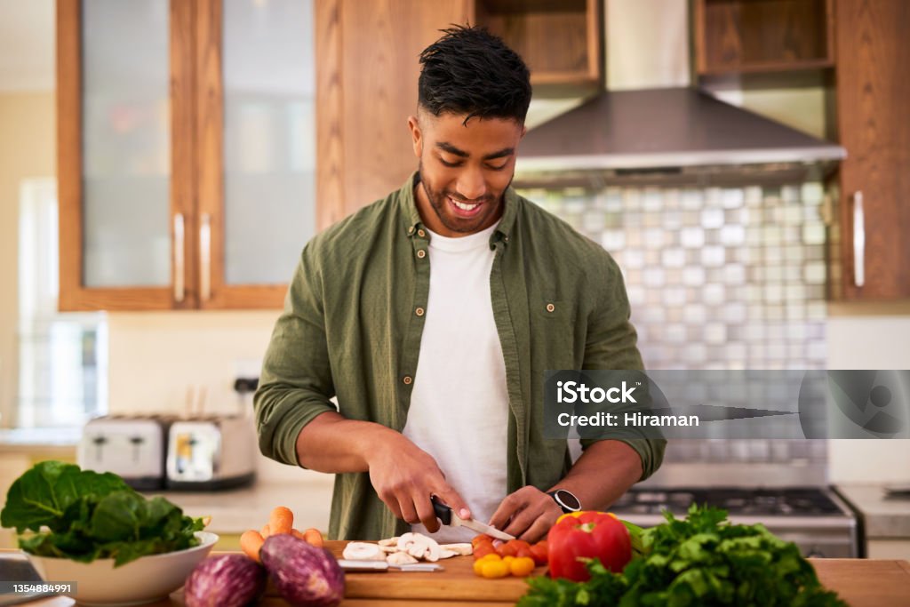 Shot of a young man preparing vegetables to cook a meal The kitchen is my happy place Men Stock Photo