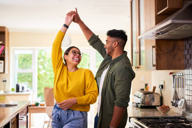shot of a young couple dancing together in their kitchen - huis stockfoto's en -beelden