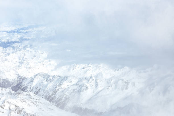 istock White clouds and mountain pics, a view from an airplane window. Top view, snowing 1354885921