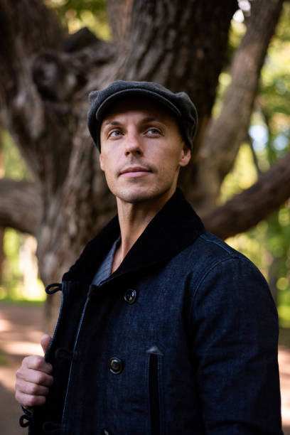 istock A man in a coat and cap walks around the city. 1354886049